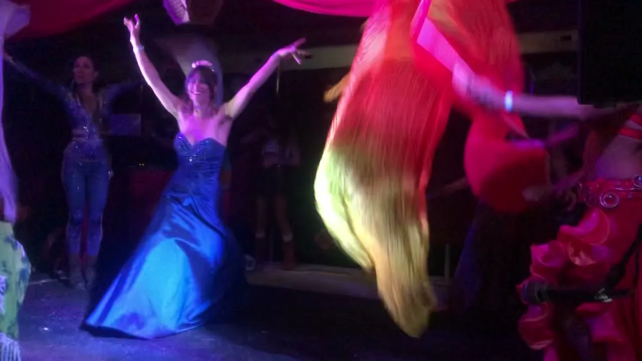 A troupe of belly dancers with silk fan veils on an indoor stage