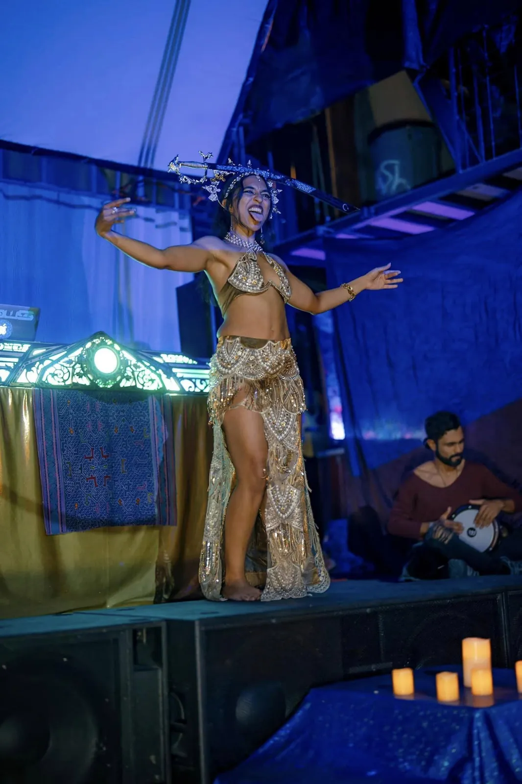 A belly dancer on stage with a live percussionist