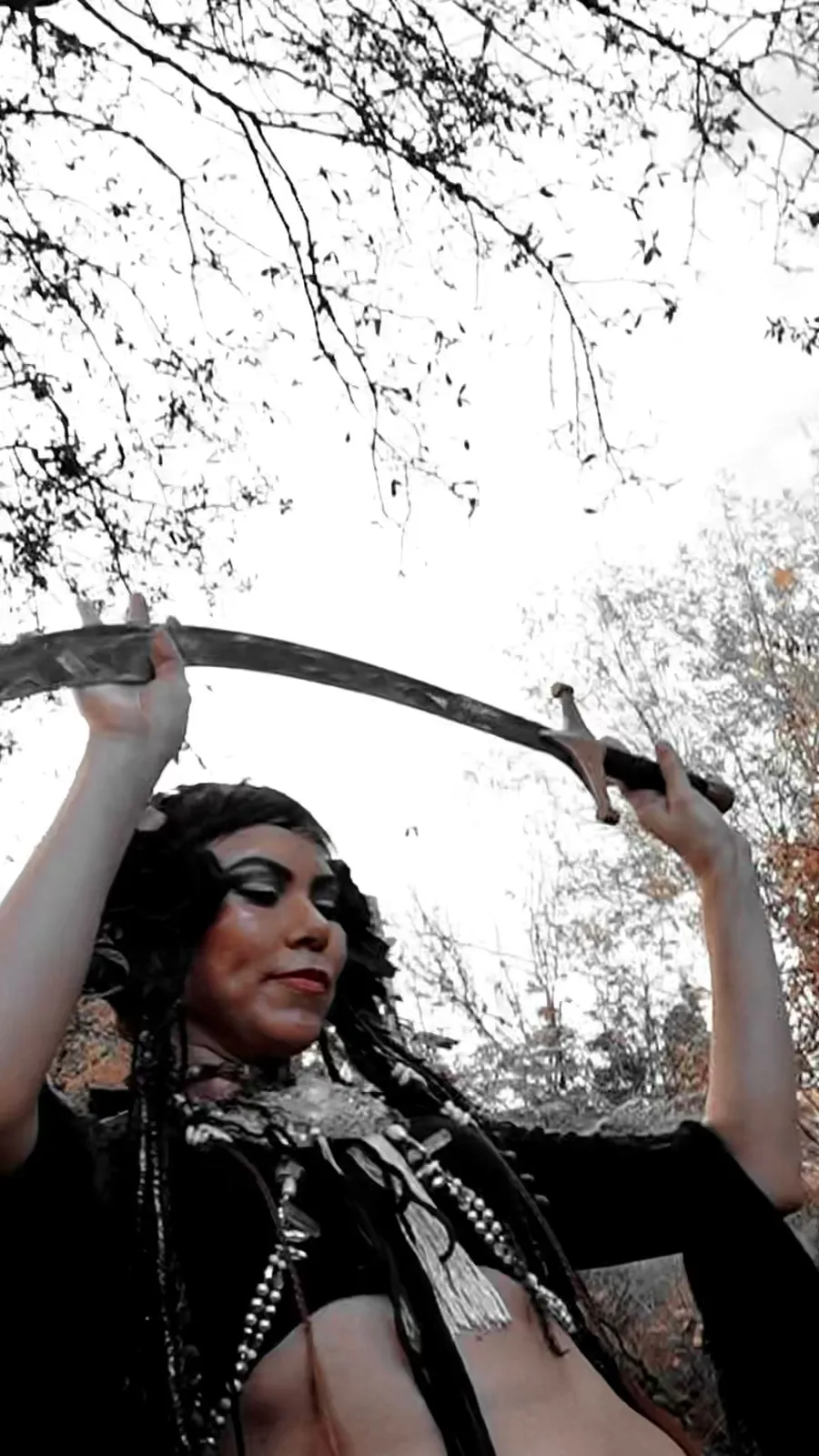 A belly dancer balances a sword overhead during an outdoor performance