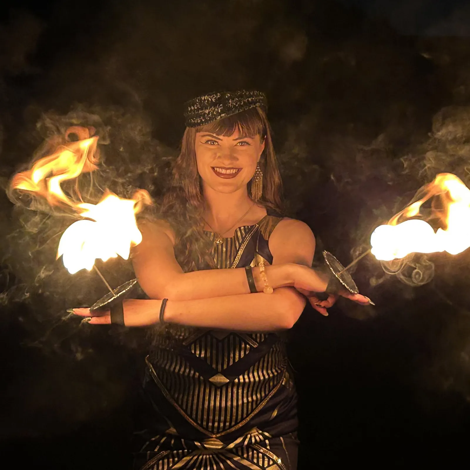 A fire performer holds two lit fire fans